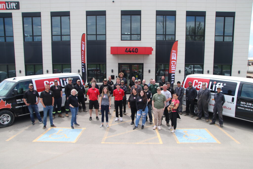 Outdoor parking lot of a large group smiling at the camera.