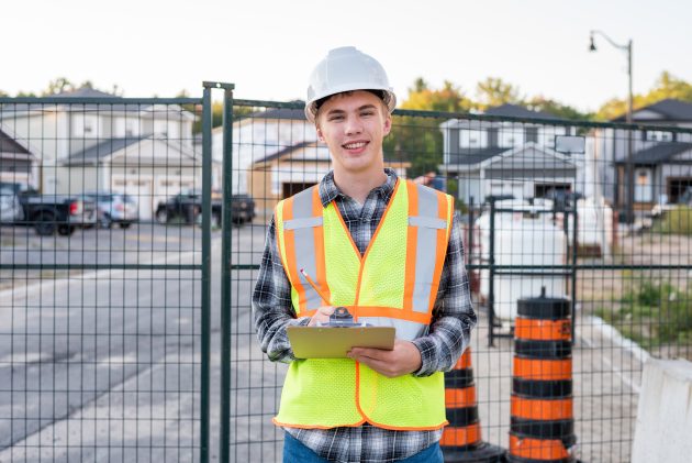 Young man construction worker smiles at the camera.